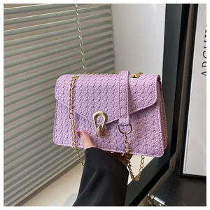 Close-up of lavender PU leather crossbody bag with woven texture and gold horseshoe buckle