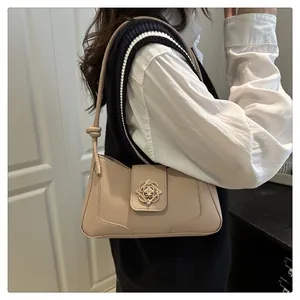 Close-up of beige shoulder bag featuring a vintage gold hollowed floral metal buckle