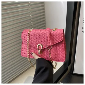 Detail of pink woven PU leather crossbody bag with golden metal clasp and chain strap