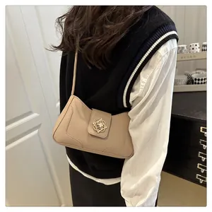 Detailed view of the vintage floral metal buckle on a beige leather underarm bag