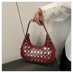Dettaglio borsa hobo a mezzaluna rosso scuro con rivetti argentati e pelle lucida