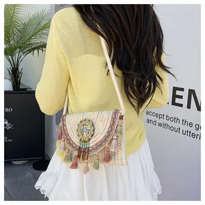 Dettaglio borsa a tracolla boho intrecciata a mano con ricami e nappe di perline