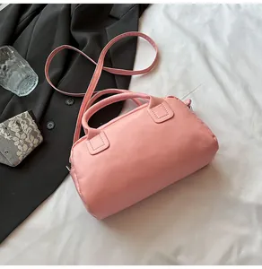 Detail of pink Boston bag with smooth leather finish and detachable strap on white fabric