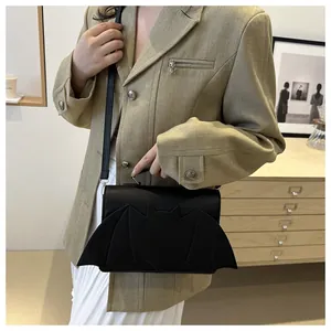 Détail du sac à main noir en forme de chauve-souris avec bandoulière sur un modèle