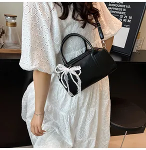 Détail du sac Boston noir avec nœuds en dentelle blanche et perles dans un décor lifestyle