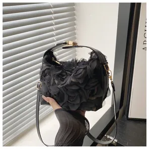 Detail of 3D mesh flower petals and golden metal clasp on black elegant evening bag