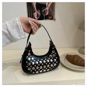 Dettaglio di una borsa hobo a mezzaluna nera con rivetti e design curvo elegante