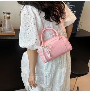 Détail du sac Boston rose avec nœud en dentelle et perle porté par un mannequin