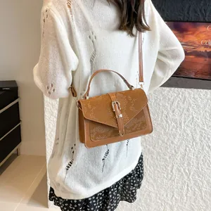 Sac bandoulière chic marron à motif serpent avec boucle porté par un mannequin