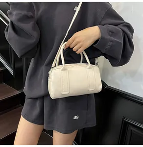 Détail du sac Boston crème avec logo embossé et texture en cuir PU de haute qualité