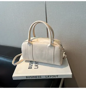 Detail view of cream Boston bag showing the soft leather texture and printed branding logo