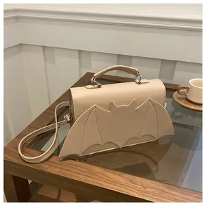 Détail d'un sac à main beige en forme d'aile de chauve-souris sur une table en bois