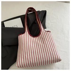 Détail du sac fourre-tout en toile à rayures rouges et blanches avec garniture en cuir