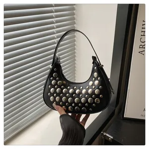 Detail of black crescent hobo bag featuring silver punk studs and matte leather finish