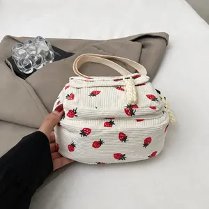 Detail shot of white corduroy mini bag with red strawberry pattern and fabric handles