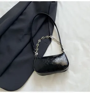 Detail of black glossy wrinkled PU leather underarm bag with silver chain accessory