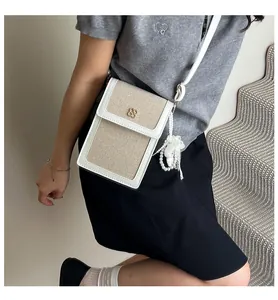 Détail du mini sac de téléphone tissé avec fermoir trèfle doré et breloque en perles