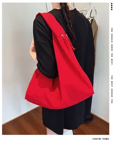 Close-up of red nylon shoulder bag worn by model showing large capacity and minimalist design