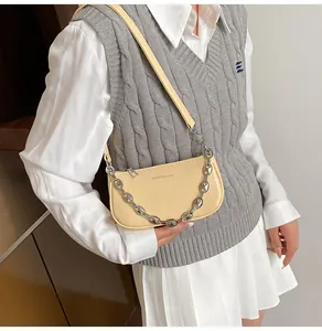Detailed view of cream-colored shoulder bag with silver chain strap and logo on model