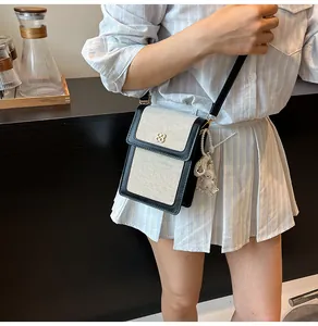 Détail de la pochette téléphone en toile avec bordure cuir et charm lapin en peluche