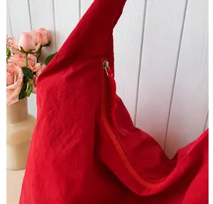 Detail of red nylon tote bag featuring a high-quality smooth zipper and wrinkled texture