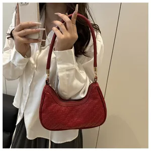 Detail of red woven shoulder bag featuring textured chevron pattern and gold metal hardware