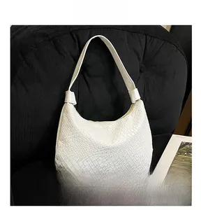 Close-up of white woven leather texture on a crescent shoulder bag with a dark background