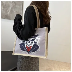 Detail of a large canvas tote bag with a gentleman skull print worn by a model