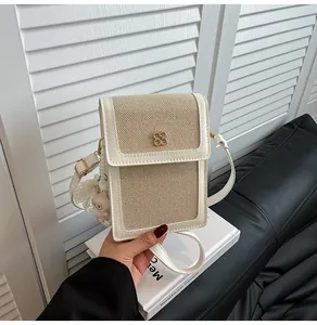 Détail de la pochette téléphone en toile beige avec boucle trèfle dorée et breloque mouton