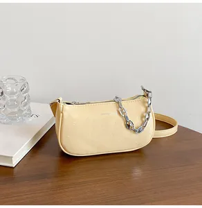 Detail of pale yellow leather shoulder bag with fine pleated texture and silver chain strap