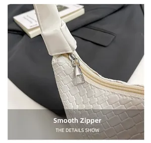 Detail of smooth silver zipper on a white textured leather tote bag with woven pattern
