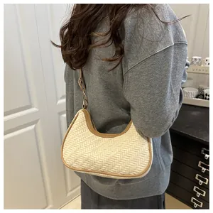Model wearing a woven hobo shoulder bag in beige with brown leather trim detailing