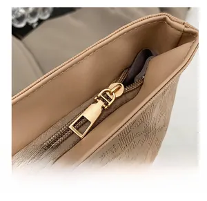 Macro view of light coffee tote bag with geometric embossing and smooth gold zipper