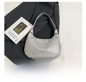 Detailed view of silver woven tote bag with smartphone for size comparison