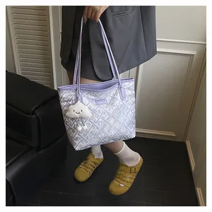 Close-up of light purple tote bag with geometric patterns and a cloud plush charm accessory
