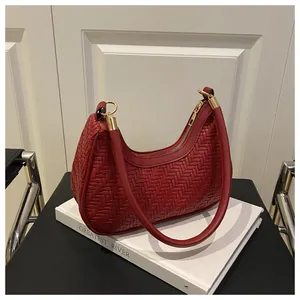 Detailed close-up of a red woven leather hobo bag with gold metal rings and zipper