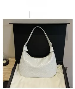 Close-up of white woven leather hobo bag with sleek zipper detail on silk background