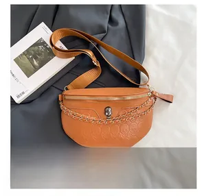 Detail of tan PU leather chest bag featuring skull embossing and decorative chain