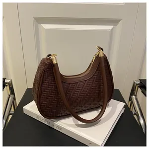 Detailed view of dark brown woven leather texture and gold zipper on crescent bag