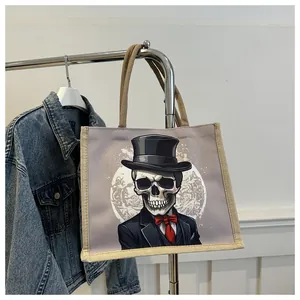 Detail of cartoon skeleton printed tote bag hanging on a rack with a denim jacket