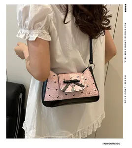 Detail of pink pleated underarm bag with black bow patterns and silver heart charm