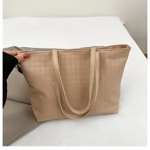 Detail of beige woven tote bag showing embossed houndstooth texture and double shoulder straps