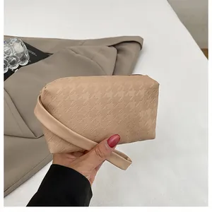 Close-up of apricot houndstooth textured PU leather clutch bag with carry strap