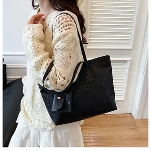 Close-up of black woven texture tote bag with matching pouch shown on a model