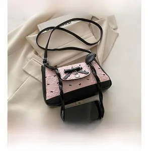 Detailed view of pink bow baguette bag with heart charm next to smartphone for scale