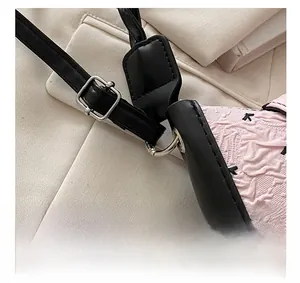 Detail view of silver hardware buckle and pink bow jacquard fabric on shoulder bag