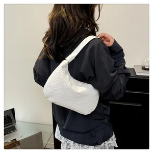 Detailed view of a white woven texture hobo bag worn as a modern shoulder bag