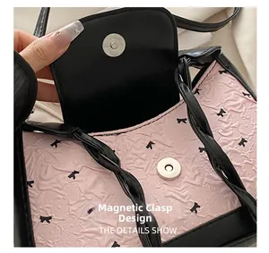 Detail of pink embossed fabric texture and magnetic snap closure on the shoulder bag