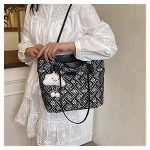 Detail of black and white geometric pattern tote bag with white plush charm and leather straps
