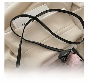 Detail of adjustable black leather strap with metal buckle on pink textured shoulder bag